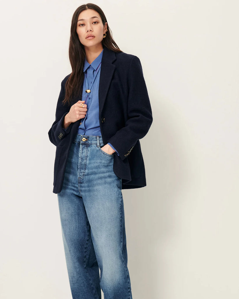 Granatowa, wełniana kurtka Madawool Navy w stylu garniturowym z lekko usztywnianymi ramionami. Ma dopasowany kołnierzyk, zapięcie na guziki z przodu i naszywane kieszenie. Posiada również ozdobne guziki przy mankietach.