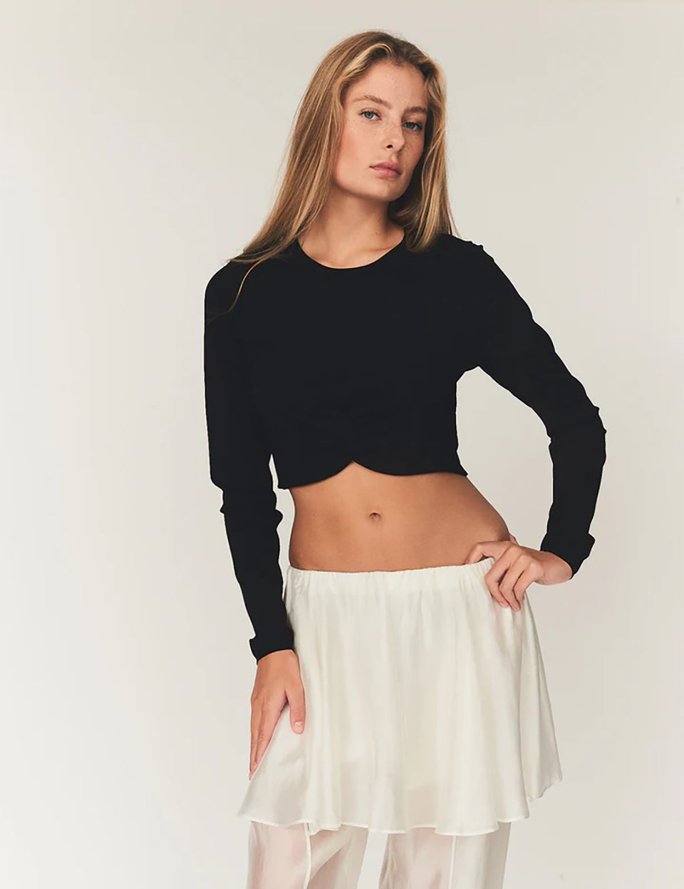 Czarny, dopasowany top Madison Black marki The Garment o minimalistycznym, wyrazistym kroju. Ma okrągły, zabudowany dekolt i długie rękawy. U dołu materiał jest zebrany i związany w supeł, co tworzy delikatne marszczenie i skróconą długość odsłaniającą brzuch. Wykonany z miękkiej, przylegającej do ciała tkaniny.

-Dopasowany krój

-Skrócona długość&nbsp;

-Zamów top w swoim standardowym rozmiarze