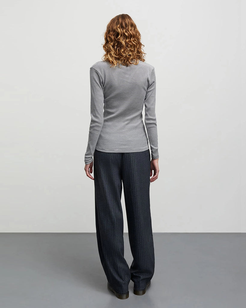Minimalistyczny longsleeve 2x2 Tuba MADS NORGAARD w cienkie, granatowo-kremowe paski. Bluzka ma okrągły dekolt, przylegający fason i wąskie, długie rękawy. Wykonany jest z elastycznej, bawełnianej tkaniny z prążkowaną fakturą