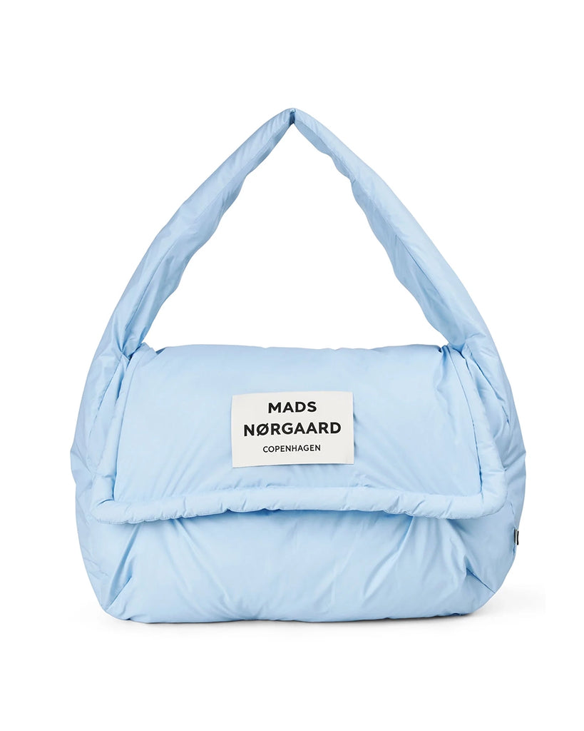 Oversizowa torba puchowa Pillow Bomb MADS NORGAARD z klapką i dużą naszywką z logo marki z prozdu. Torba posiada rączkę do wygodnego zawieszenia na ramieniu.