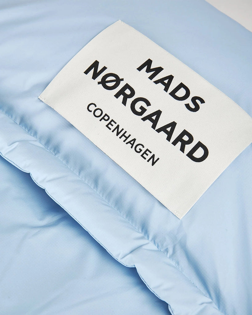 Oversizowa torba puchowa Pillow Bomb MADS NORGAARD z klapką i dużą naszywką z logo marki z prozdu. Torba posiada rączkę do wygodnego zawieszenia na ramieniu.