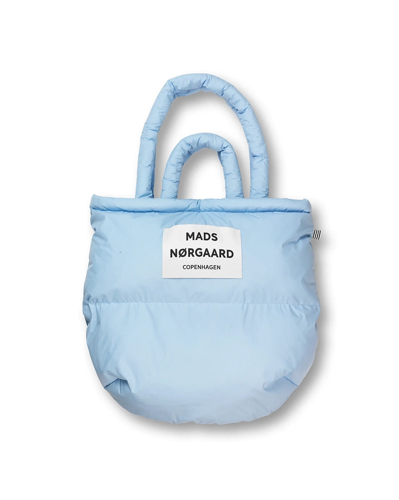 Duża, puchowa torba Pillow duńskiej marki MADS NØRGAARD w stylu shopper. Posiada dwie, krótkie rączki do wygodnego trzymania w dłoni i dwie dłuższe do zawieszenia na ramieniu. Wewnątrz posiada kieszonkę na najważniejsze rzeczy takie jak telefon, portfel czy klucze.