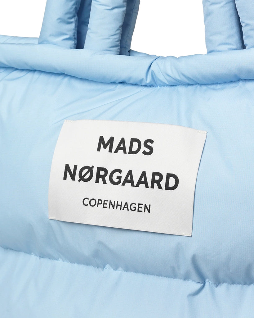 Duża, puchowa torba Pillow duńskiej marki MADS NØRGAARD w stylu shopper. Posiada dwie, krótkie rączki do wygodnego trzymania w dłoni i dwie dłuższe do zawieszenia na ramieniu. Wewnątrz posiada kieszonkę na najważniejsze rzeczy takie jak telefon, portfel czy klucze.