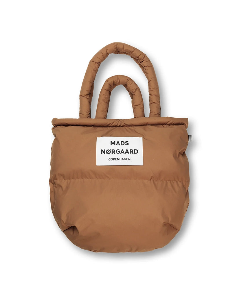 Duża, puchowa torba Pillow duńskiej marki MADS NØRGAARD w stylu shopper. Posiada dwie, krótkie rączki do wygodnego trzymania w dłoni i dwie dłuższe do zawieszenia na ramieniu
