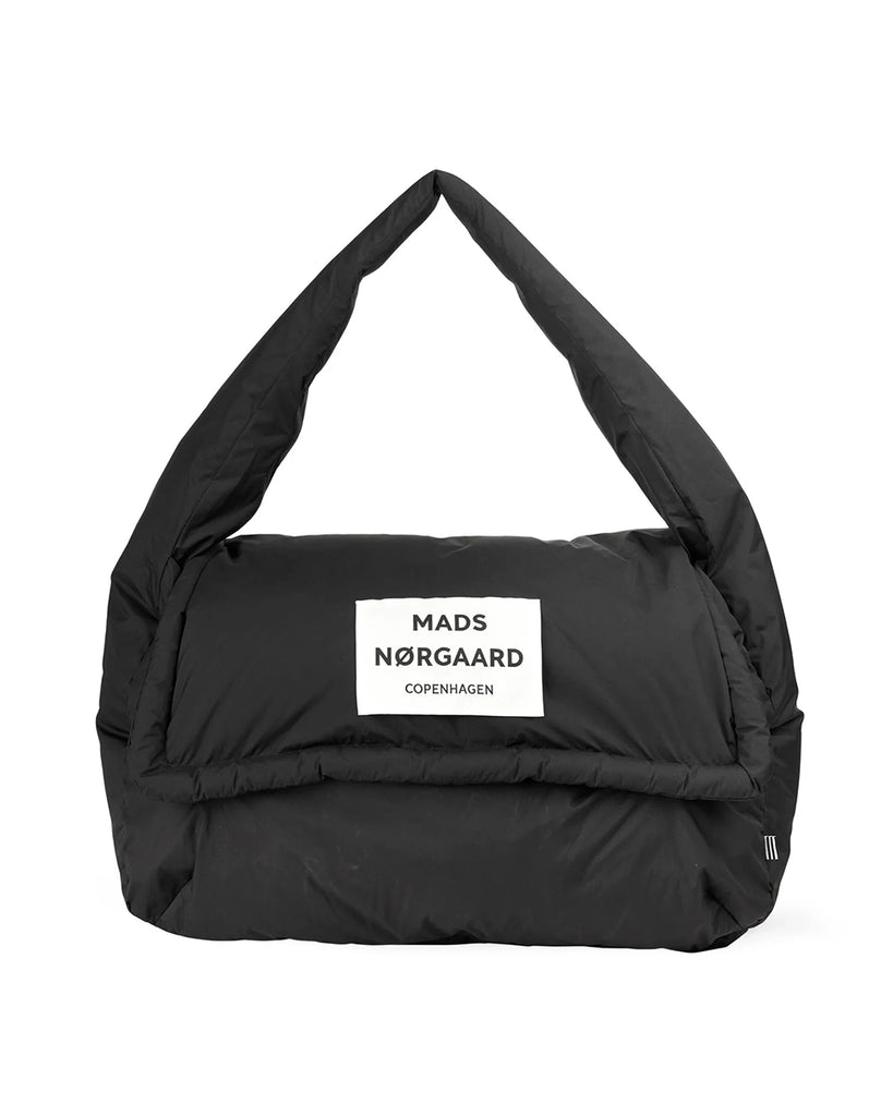 Oversizowa torba puchowa Pillow Bomb MADS NORGAARD z klapką i dużą naszywką z logo marki z prozdu. Torba posiada rączkę do wygodnego zawieszenia na ramieniu.