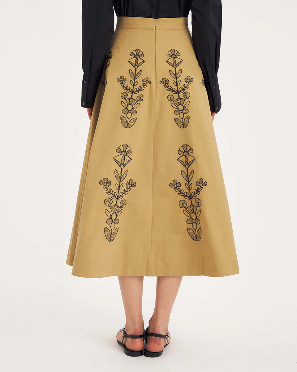 Rozkloszowana, trapezowa spódnica Maria Beige marki Antik Batik o klasycznej długości midi, sięgającej do połowy łydki. Ma wysoką, gładką talię z wyraźnie zaznaczonym, szerokim pasem. Głównym elementem dekoracyjnym są duże, pionowe hafty roślinne i kwiatowe w ciemnym kolorze. Haft układa się symetrycznie, w pionowe rzędy, co optycznie wydłuża sylwetkę i nadaje całości tradycyjny, rzemieślniczy charakter.&nbsp;

-Długość midi

-Wysoki stan

-Ozdobne hafty kwiatowe i roślinne

-Zamów spódnicę w swoim standard