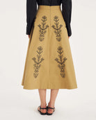 Rozkloszowana, trapezowa spódnica Maria Beige marki Antik Batik o klasycznej długości midi, sięgającej do połowy łydki. Ma wysoką, gładką talię z wyraźnie zaznaczonym, szerokim pasem. Głównym elementem dekoracyjnym są duże, pionowe hafty roślinne i kwiatowe w ciemnym kolorze. Haft układa się symetrycznie, w pionowe rzędy, co optycznie wydłuża sylwetkę i nadaje całości tradycyjny, rzemieślniczy charakter.&nbsp;

-Długość midi

-Wysoki stan

-Ozdobne hafty kwiatowe i roślinne

-Zamów spódnicę w swoim standard