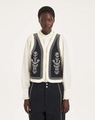 Krótka kamizelka Maria Black marki Antik Batik o wyraźnym, etnicznym charakterze nawiązującym do stylu boho-chic. Jest to fason sięgający do linii bioder, z otwartym przodem, bez widocznego zapięcia. Przód kamizelki zdobi bogaty, symetryczny haft w kontrastującym kolorze. Wszystkie krawędzie zostały obszyte ozdobną, wzorzystą taśmą z geometrycznym haftem. Zestaw ją z ulubionymi spodniami oraz luźną, białą koszulą z bufiastymi rękawami i wysoką stójką.

-Krótki fason

-Symetryczne hafty

-Zamów kamizelkę w s