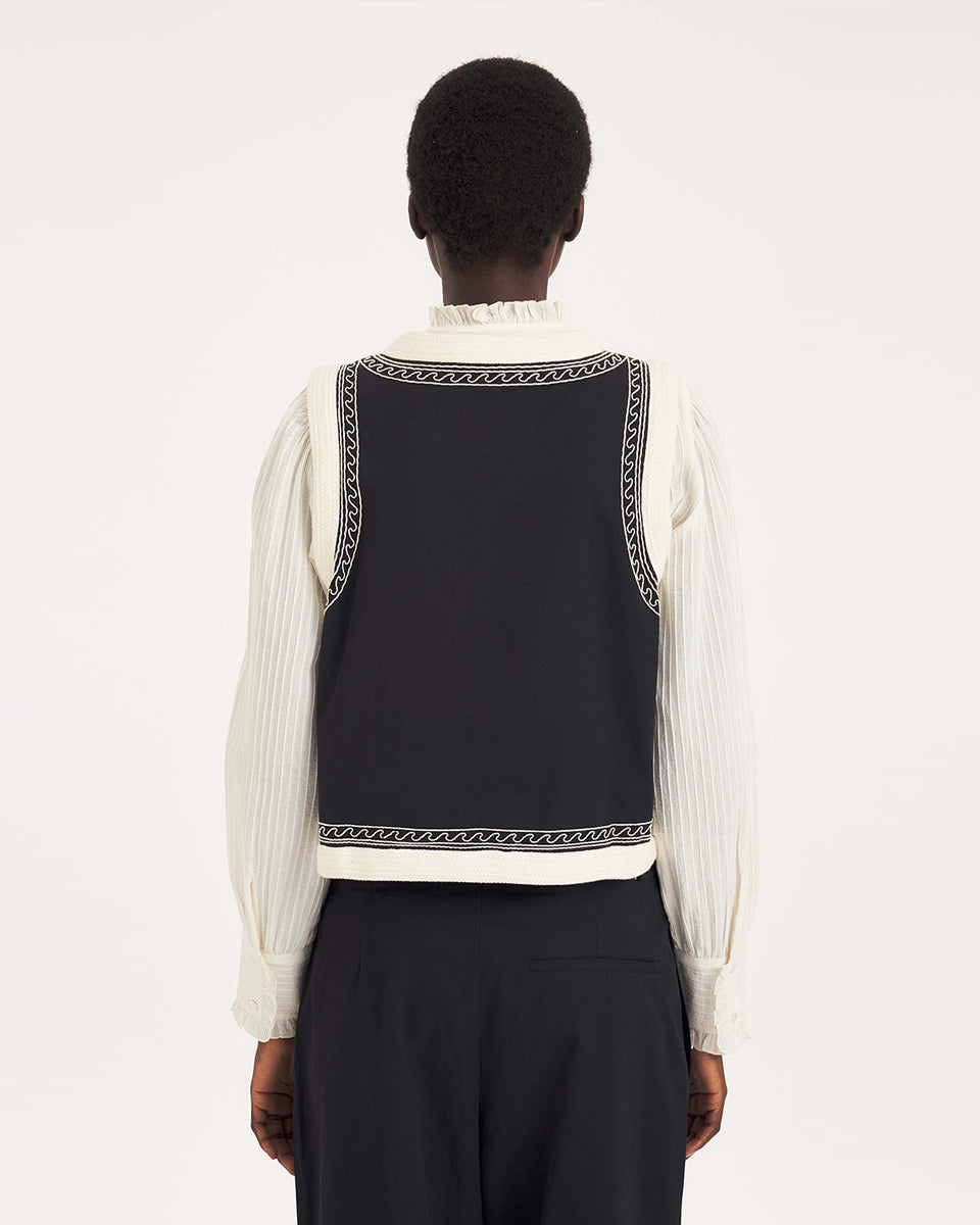 Krótka kamizelka Maria Black marki Antik Batik o wyraźnym, etnicznym charakterze nawiązującym do stylu boho-chic. Jest to fason sięgający do linii bioder, z otwartym przodem, bez widocznego zapięcia. Przód kamizelki zdobi bogaty, symetryczny haft w kontrastującym kolorze. Wszystkie krawędzie zostały obszyte ozdobną, wzorzystą taśmą z geometrycznym haftem. Zestaw ją z ulubionymi spodniami oraz luźną, białą koszulą z bufiastymi rękawami i wysoką stójką.

-Krótki fason

-Symetryczne hafty

-Zamów kamizelkę w s