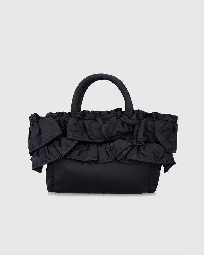 Torba typu tote 7187 Mini Shopper Black marki GANNI z uchwytami i paskiem na ramię. Posiada jedną dużą komorę z wewnętrzną kieszenią zapinaną na zamek. U dołu znajduje się niewielkie logo marki. Wyjątkowości dodaje zdobienie w postaci falbanek. Zaprojektowana, aby pomieścić najpotrzebniejsze drobiazgi.