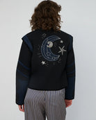 Krótka, czarno-granatowa kurtka Moon&amp;Star Embroidered marki STELLA NOVA o geometrycznym kroju, z wysokim kołnierzem typu stójka i zapięciem na guziki z przodu. Wyróżnia się kontrastowymi wstawkami na klatce piersiowej, ramionach i przy dużych, półokrągłych kieszeniach. Z tyłu posiada haft z motywem gwiazd i księżyca. Sylwetka jest prosta, ale dzięki strukturze i detalom wygląda bardzo architektonicznie i modnie. Wykonana z bawełny organicznej.