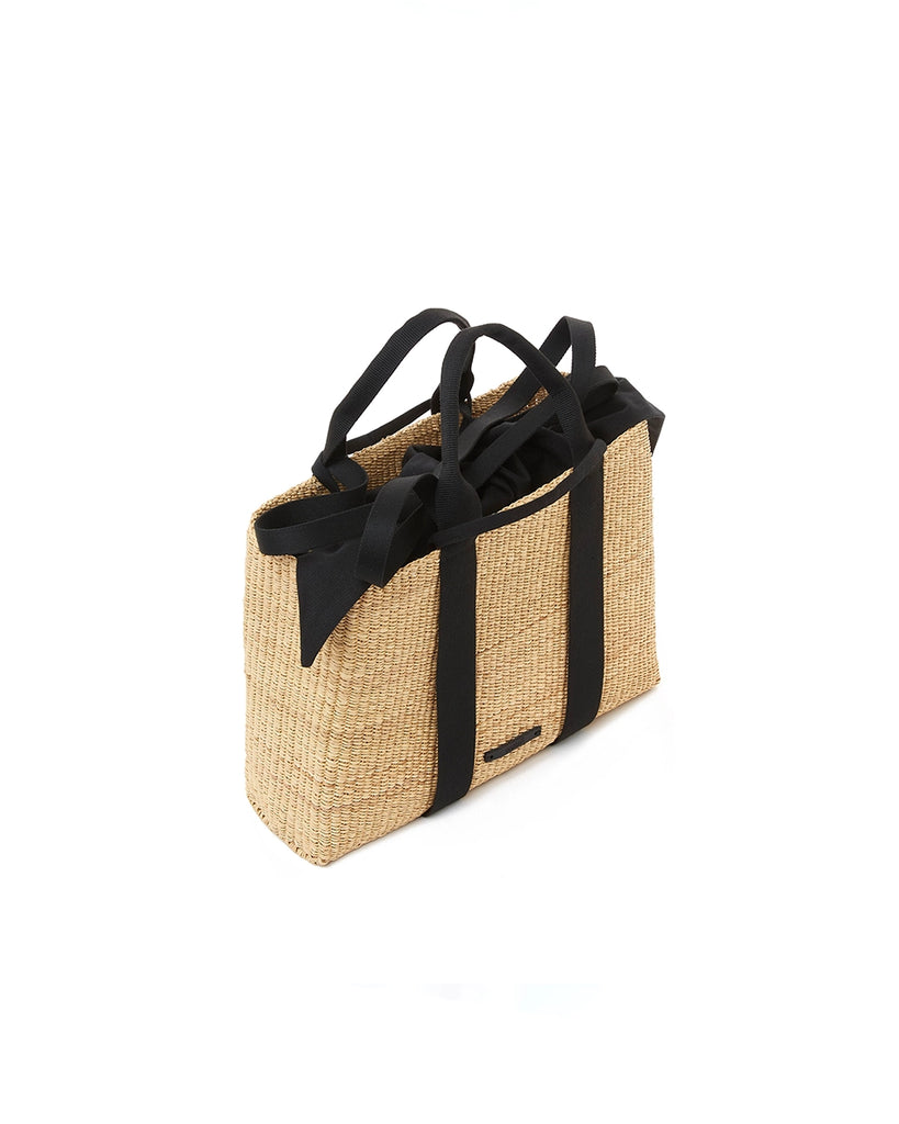 Średniej wielkości, ręcznie pleciony kosz JEROME - NATURAL x BLACK HDL x BLACK COTTON francuskiej marki Muun. Posiada prostokątny kształt, dwie mocne, plecione materiałowe rączki w kolorze ciemnozielonym do wygodnego trzymania w dłoni i zawieszenia na ramieniu. Wewnątrz koszyka znajduje się wiązana, wyciągana bawełniana, czarna torebka