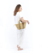 Średniej wielkości, ręcznie pleciony kosz GEORGE - NATURAL x BEIGE HDL x NATURAL LINEN francuskiej marki Muun. Posiada trapezowy kształt, dwie mocne, materiałowe rączki do wygodnego trzymania w dłoni oraz długi, cienki pasek do zawieszenia na ramieniu. 