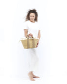 Średniej wielkości, ręcznie pleciony kosz GEORGE - NATURAL x BEIGE HDL x NATURAL LINEN francuskiej marki Muun. Posiada trapezowy kształt, dwie mocne, materiałowe rączki do wygodnego trzymania w dłoni oraz długi, cienki pasek do zawieszenia na ramieniu. 
