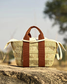 Średniej wielkości, ręcznie pleciony, częściowo ażurowy kosz GEORGE NET - NATURAL x RUST HDL x ECRU COTTON francuskiej marki Muun. Posiada trapezowy kształt, dwie mocne, materiałowe rączki do wygodnego trzymania w dłoni oraz długi, cienki pasek do zawieszenia na ramieniu.