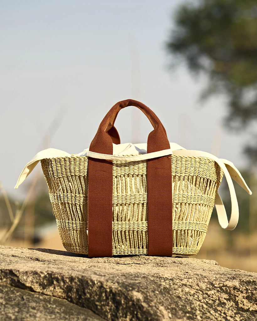 Średniej wielkości, ręcznie pleciony, częściowo ażurowy kosz GEORGE NET - NATURAL x RUST HDL x ECRU COTTON francuskiej marki Muun. Posiada trapezowy kształt, dwie mocne, materiałowe rączki do wygodnego trzymania w dłoni oraz długi, cienki pasek do zawieszenia na ramieniu.