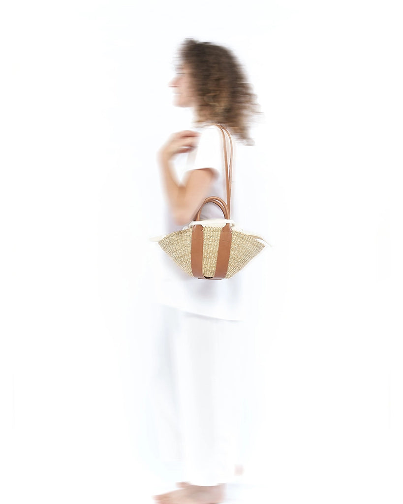 Mała, ręcznie pleciona torebka koszyk MINI SOPHIE - NATURAL x Tan HDL x Ecru COTTON francuskiej marki Muun. Posiada wachlarzowy kształt, dwie mocne, skórzane, brązowe rączki do wygodnego trzymania w dłoni oraz długi, cienki pasek do zawieszenia na ramieniu. 
