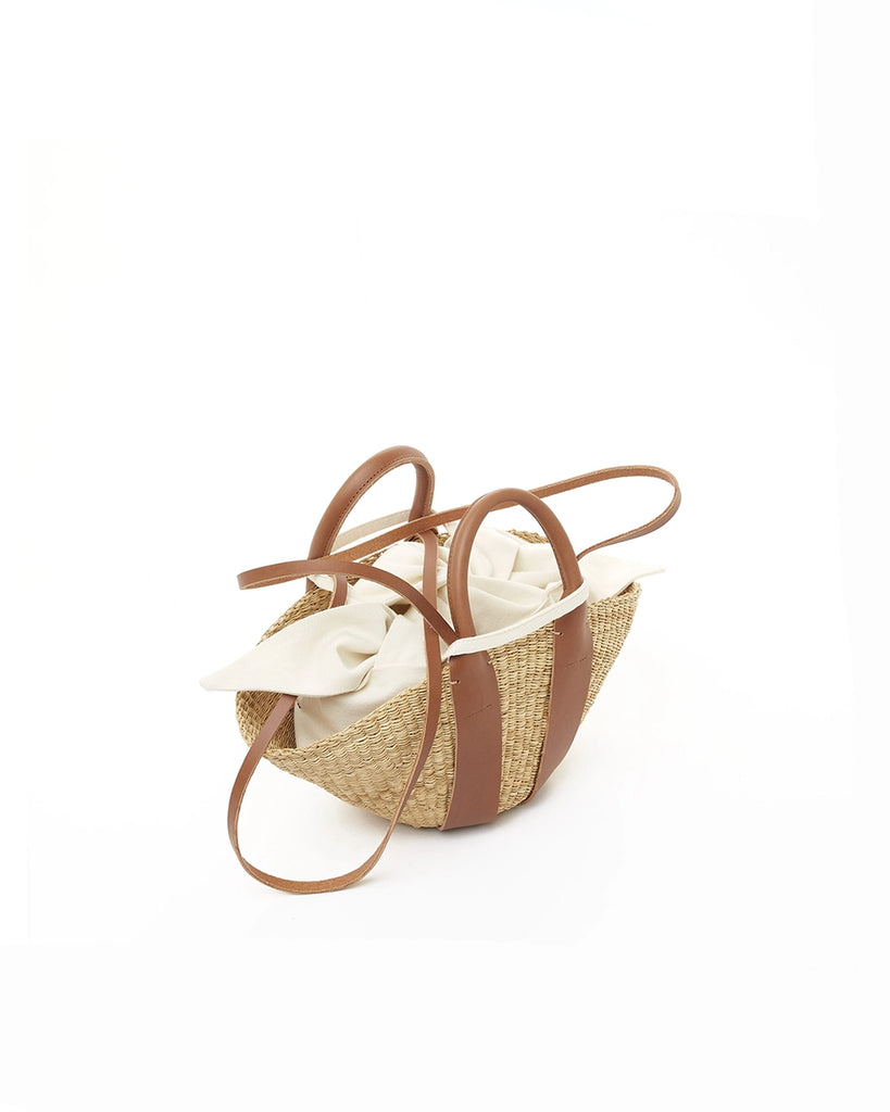 Mała, ręcznie pleciona torebka koszyk MINI SOPHIE - NATURAL x Tan HDL x Ecru COTTON francuskiej marki Muun. Posiada wachlarzowy kształt, dwie mocne, skórzane, brązowe rączki do wygodnego trzymania w dłoni oraz długi, cienki pasek do zawieszenia na ramieniu. 