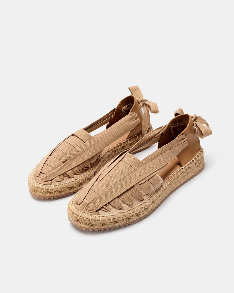 Ręcznie wykonane, hiszpańskie, wkładane espadryle SOC Trail Naguisa. Z przodu wykonane z płótna i plecione za pomocą bawełnianej, szerokiej wstążki wiązanej na kokardę na pięcie. Zapiętek butów wykonany jest z miękkiej, krowiej skóry