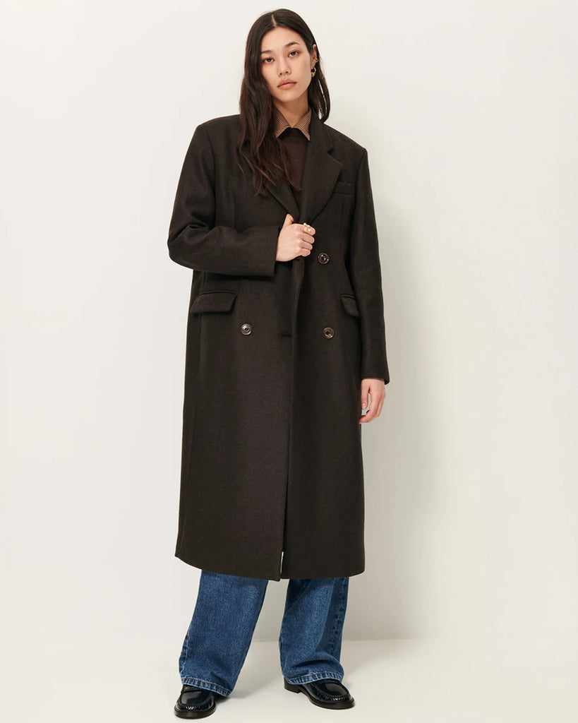 Długi, prosty, dwurzędowy płaszcz NARA Teck francuskiej marki Sessun wykonany z wełnianej tkaniny z dwukolorową przędzą o melanżowym wykończeniu. Ma usztywnione ramiona, dwie kieszenie wpuszczane patkami z przodu i rozcięcie z tyłu. Zapięcie dwurzędowe.&nbsp;