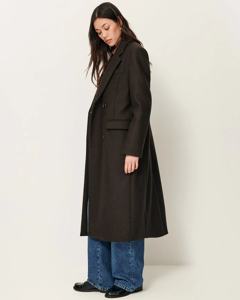 Długi, prosty, dwurzędowy płaszcz NARA Teck francuskiej marki Sessun wykonany z wełnianej tkaniny z dwukolorową przędzą o melanżowym wykończeniu. Ma usztywnione ramiona, dwie kieszenie wpuszczane patkami z przodu i rozcięcie z tyłu. Zapięcie dwurzędowe.&nbsp;