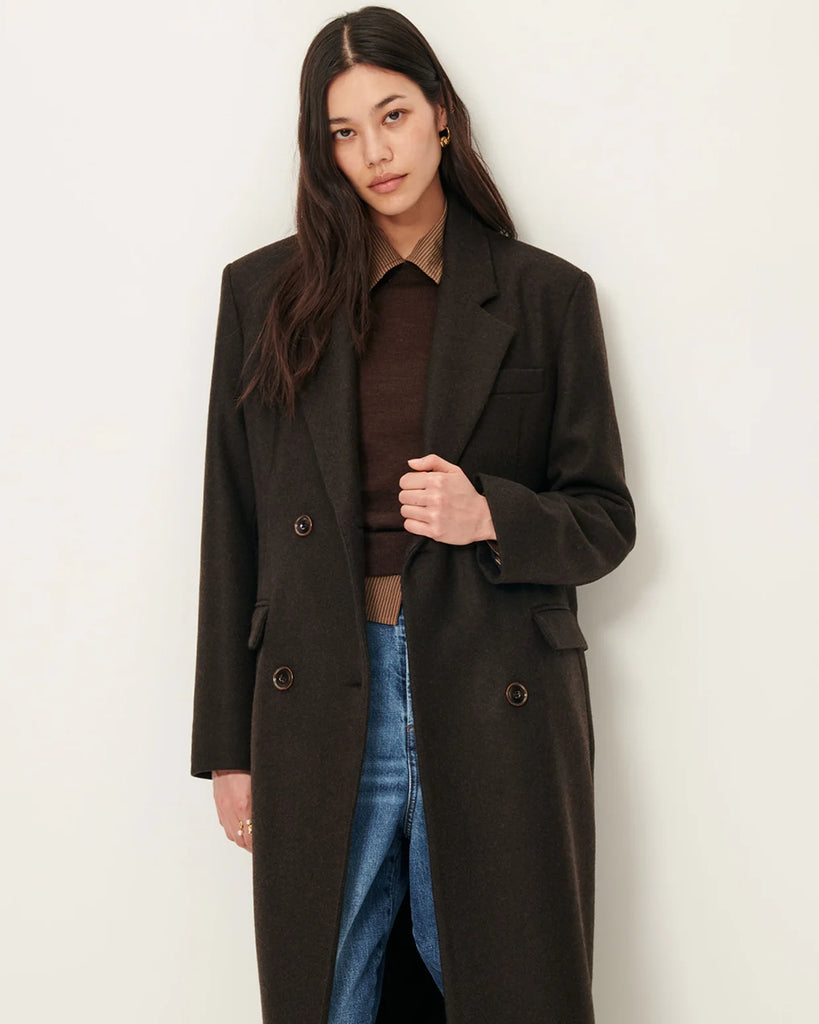 Długi, prosty, dwurzędowy płaszcz NARA Teck francuskiej marki Sessun wykonany z wełnianej tkaniny z dwukolorową przędzą o melanżowym wykończeniu. Ma usztywnione ramiona, dwie kieszenie wpuszczane patkami z przodu i rozcięcie z tyłu. Zapięcie dwurzędowe.&nbsp;