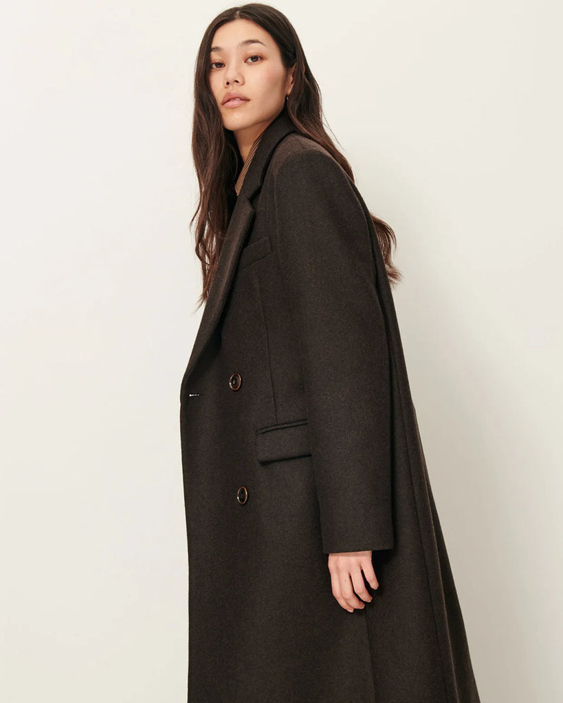 Długi, prosty, dwurzędowy płaszcz NARA Teck francuskiej marki Sessun wykonany z wełnianej tkaniny z dwukolorową przędzą o melanżowym wykończeniu. Ma usztywnione ramiona, dwie kieszenie wpuszczane patkami z przodu i rozcięcie z tyłu. Zapięcie dwurzędowe.&nbsp;