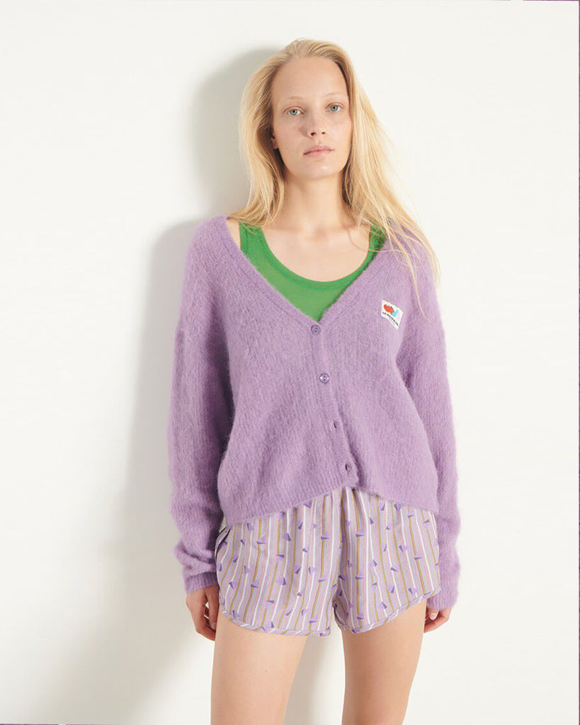 Oversizowy, miękki kardigan Nenybay Violet marki American Vintage z długim rękawem i dekoltem w serek. Zapinany na guziki. Posiada naszywkę z logo na piersi. Zakończony ściągaczami. Wykonany z lekkiej dzianiny z alpaką. Noś go samodzielnie lub połącz z innymi elementami garderoby, aby stworzyć warstwowy, codzienny look.&nbsp;