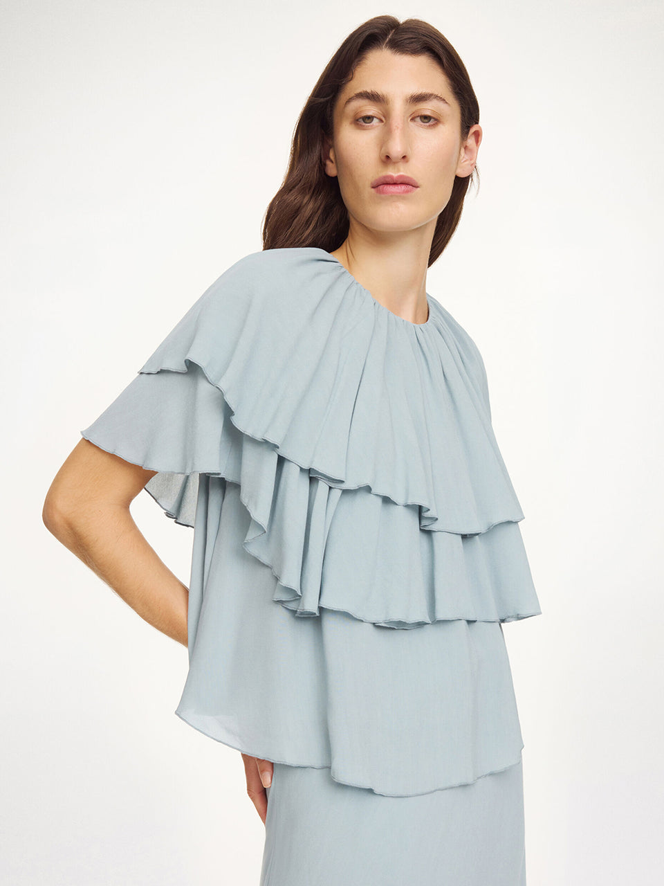 Luźny, błękitny top Nina Arona Blue By Malene Birger z okrągłym dekoltem i wiązaniem z tyłu. Składa się z kilku, półprzezroczystych warstw. Pierwsza falbana opada na ramiona, tworząc efekt 'rękawa skrzydełka'. Wykonany z wiskozy.&nbsp;

-Luźny, swobodny fason

-Bez rękawów&nbsp;

-Zamów w swoim standardowym rozmiarze&nbsp;