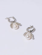 Efektowne, wiszące kolczyki PEARL OCTOPUSS.Y BABY PARIS SILVER z angielskim zapięciem. Złożone z grubego kółka i ściąganej zawieszki z dużą, naturalną perłą i połyskującym elementem wysadzanym drobnymi kryształami.
