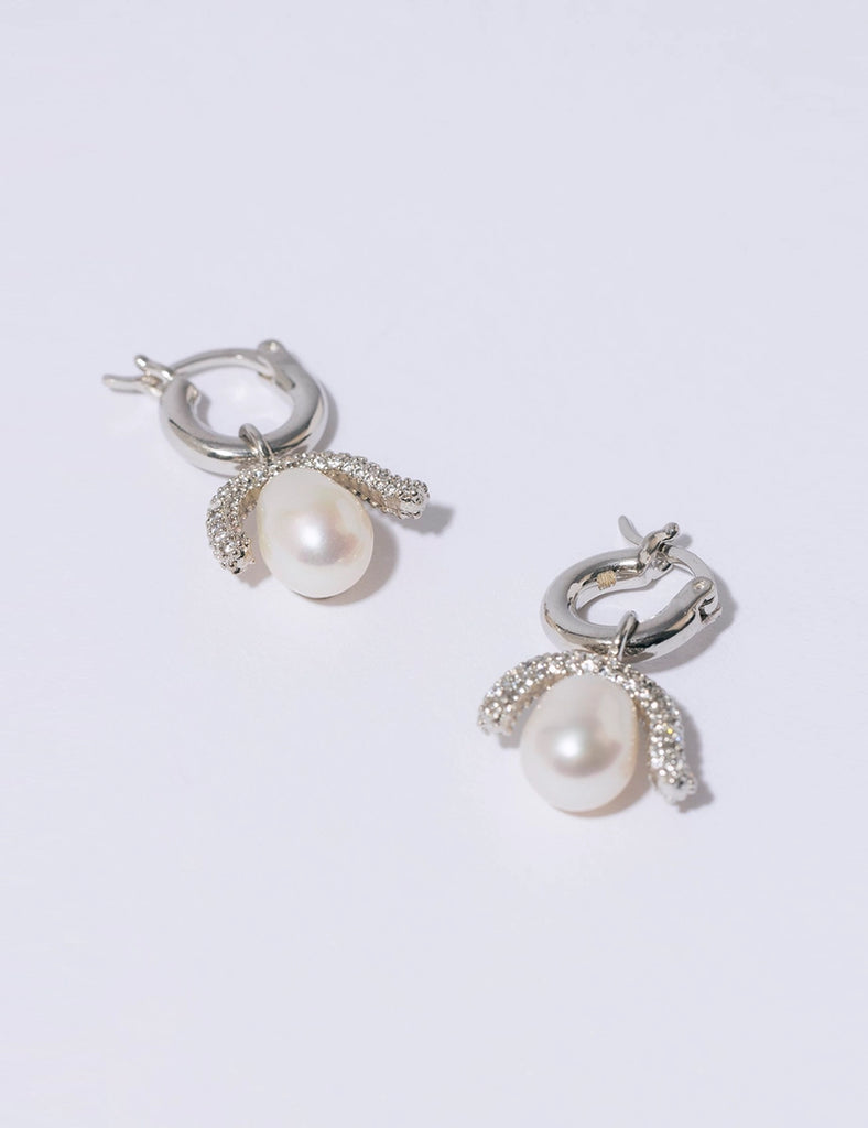 Efektowne, wiszące kolczyki PEARL OCTOPUSS.Y BABY PARIS SILVER z angielskim zapięciem. Złożone z grubego kółka i ściąganej zawieszki z dużą, naturalną perłą i połyskującym elementem wysadzanym drobnymi kryształami.
