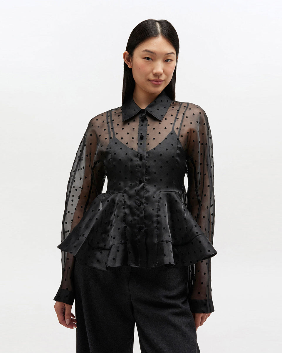 Efektowna koszula Organza Peplum Black marki GANNI z widocznym odcięciem w talii i mocno rozkloszowanym dołem. Posiada tradycyjny kołnierzyk i długie, proste rękawy zakończone mankietami. Zapinana z przodu na guziki. Prześwitujący materiał zdobiony jest klasycznym wzorem polka dots.&nbsp;

-Efekt baskinki

-Wzór polka dots

-Zamów w swoim standardowym rozmiarze