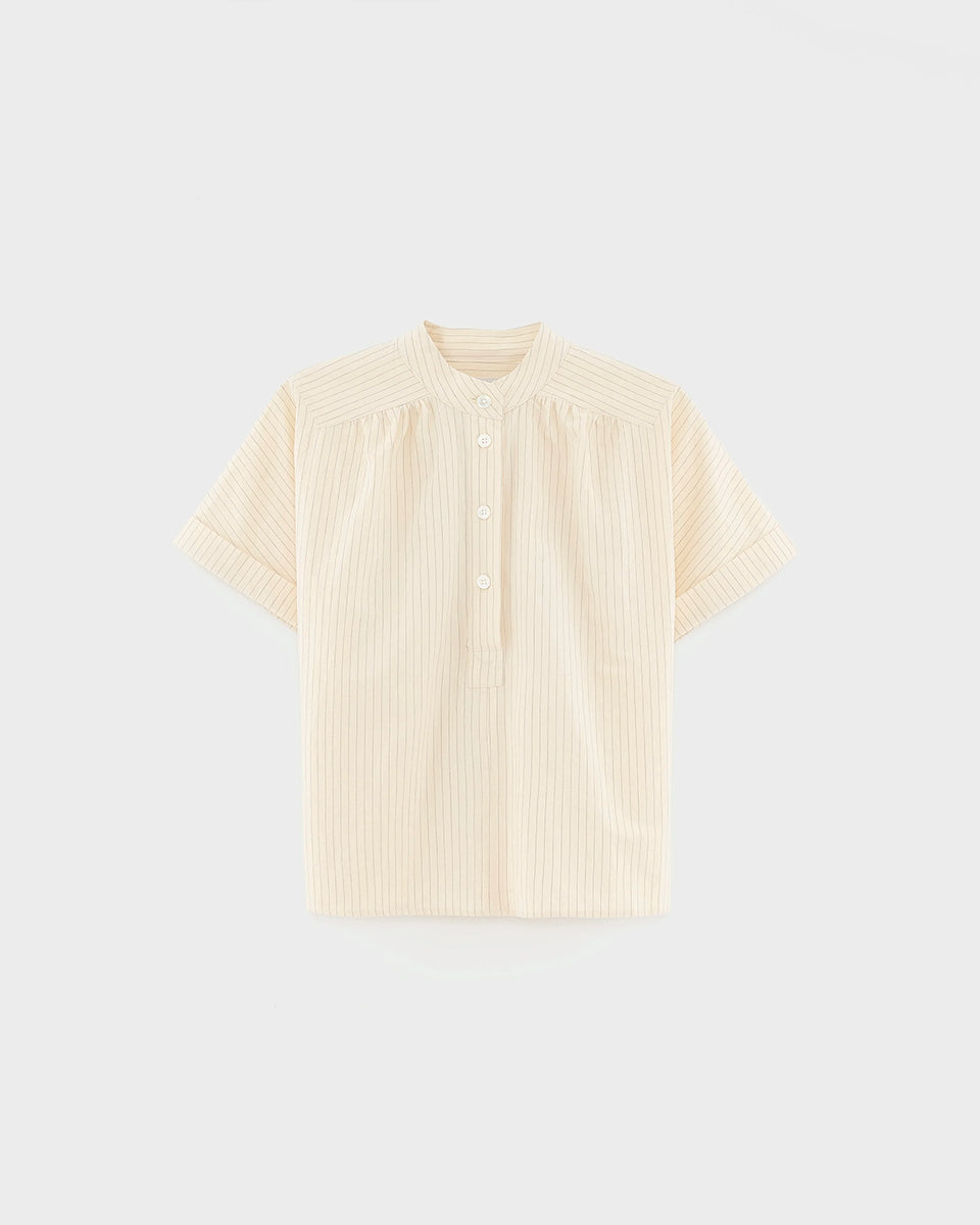 Pudełkowa bluzka Pear61 Stripe A marki BELLEROSE z półotwartym kołnierzykiem typu stójka i marszczeniami na ramionach. Bluzka ma krótki krój i krótkie, szerokie rękawy o obniżonej linii ramion. Po bokach posiada rozcięcia. Zapinana na małe guziczki kończące się w połowie klatki piersiowej. Wykonana z miękkiej mieszanki bawełnianej.

-Pudełkowy krój

-Kołnierzyk

-Marszczenia na ramionach