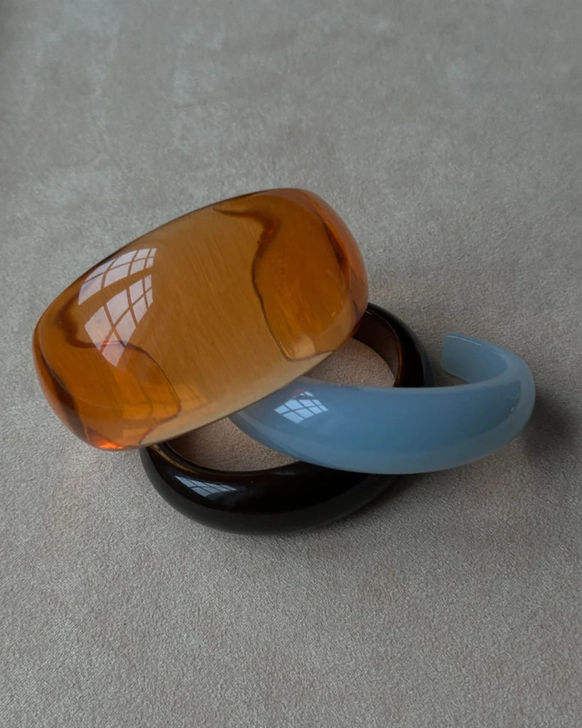 Gruba bransoletka z żywicy syntetycznej w kształcie litery C.