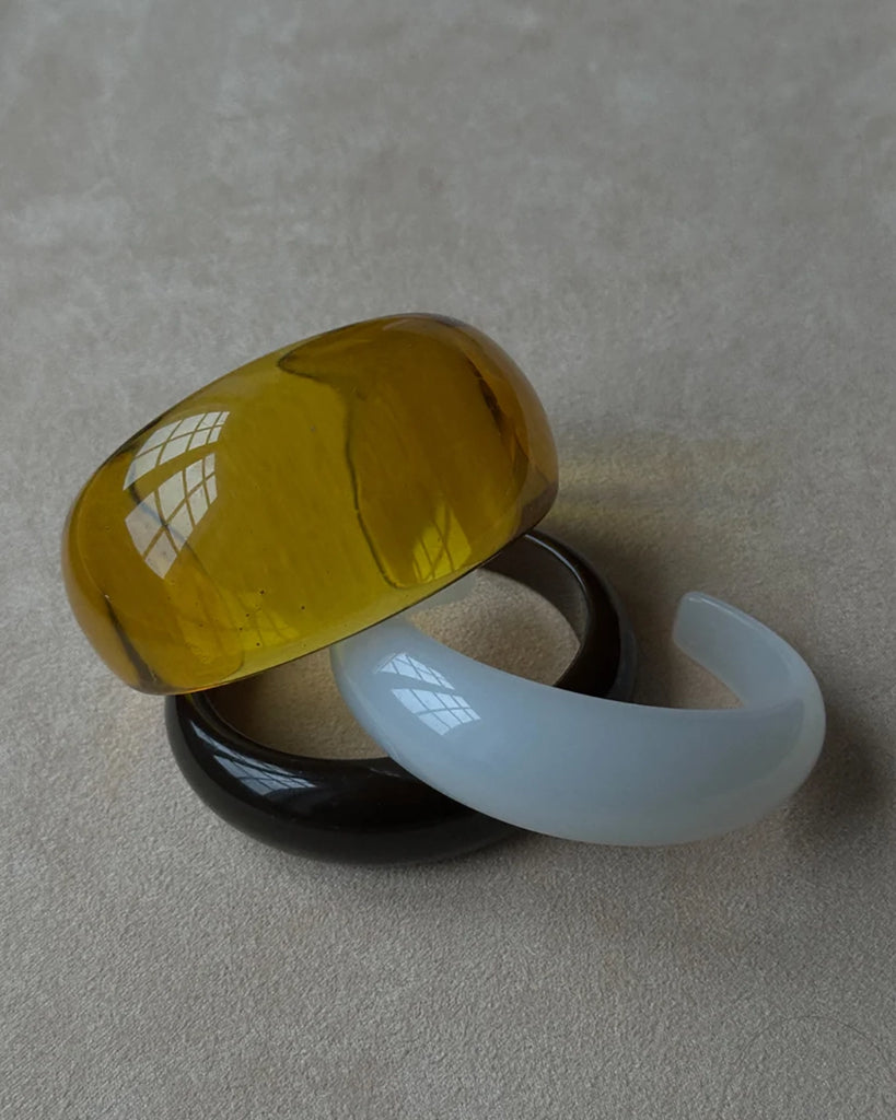 Gruba bransoletka z żywicy syntetycznej w kształcie litery C.