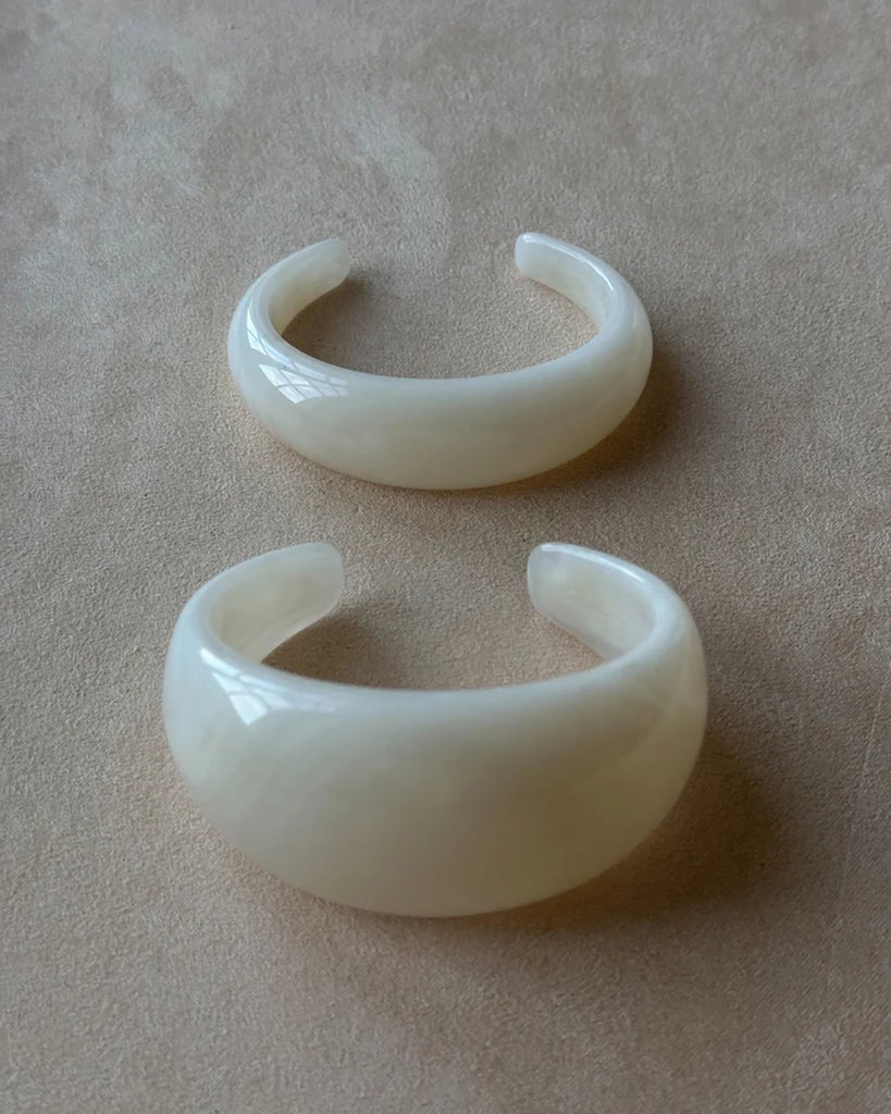 Gruba bransoletka z żywicy syntetycznej w kształcie litery C.