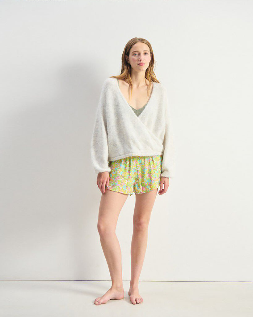 Miękki, krótki sweter NUN18 Polar Melange marki American Vintage z długimi rękawami i głębokim, skrzyżowanym kołnierzem. Wykończony ściągaczami. Wykonany z ciepłej dzianiny z alpaką. Jego kulisty kształt i kopertowy dekolt sprawiają, że jest to kobiecy, a zarazem wygodny element garderoby. Noś go z jeansami, spódnicą lub legginsami.&nbsp;