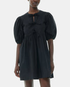 Luźna, czarna sukienka 9005 Poplin Mini Dress Black marki GANNI z okrągłym dekoltem i krótkimi, bufiastymi rękawami, które kończą się nad łokciem. Wiązana z przodu za pomocą sznurków. Odcięta wysoko w talii i rozkloszowana w dół. Wykonana z bawełny organicznej.

-Luźny fason

-100% bawełna organiczna

-Zamów w swoim standardowym rozmiarze