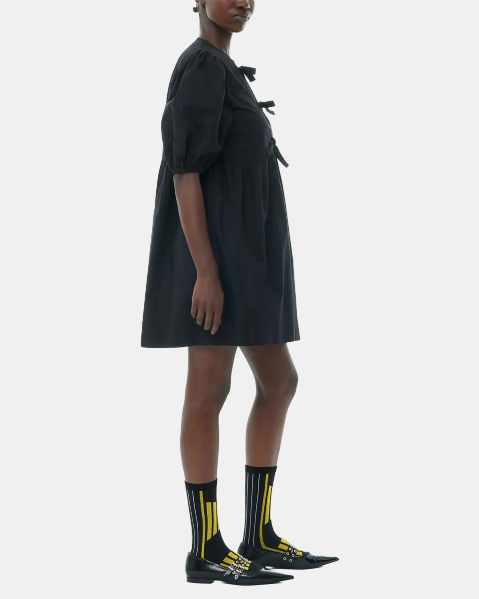 Luźna, czarna sukienka 9005 Poplin Mini Dress Black marki GANNI z okrągłym dekoltem i krótkimi, bufiastymi rękawami, które kończą się nad łokciem. Wiązana z przodu za pomocą sznurków. Odcięta wysoko w talii i rozkloszowana w dół. Wykonana z bawełny organicznej.

-Luźny fason

-100% bawełna organiczna

-Zamów w swoim standardowym rozmiarze