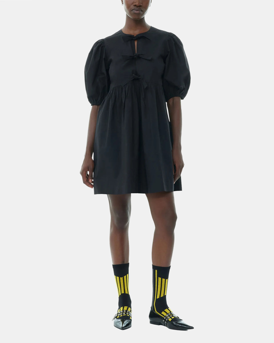 Luźna, czarna sukienka 9005 Poplin Mini Dress Black marki GANNI z okrągłym dekoltem i krótkimi, bufiastymi rękawami, które kończą się nad łokciem. Wiązana z przodu za pomocą sznurków. Odcięta wysoko w talii i rozkloszowana w dół. Wykonana z bawełny organicznej.

-Luźny fason

-100% bawełna organiczna

-Zamów w swoim standardowym rozmiarze