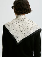 Klasyczna, piękna chusta Poula Black By Malene Birger w ponadczasowy wzór polka dots i kontrastową krawędzią. Wykonana z luksusowego jedwabiu. Zawiąż ją na szyi, nadgarstku lub rączce torebki.