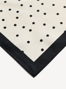 Klasyczna, piękna chusta Poula Black By Malene Birger w ponadczasowy wzór polka dots i kontrastową krawędzią. Wykonana z luksusowego jedwabiu. Zawiąż ją na szyi, nadgarstku lub rączce torebki.