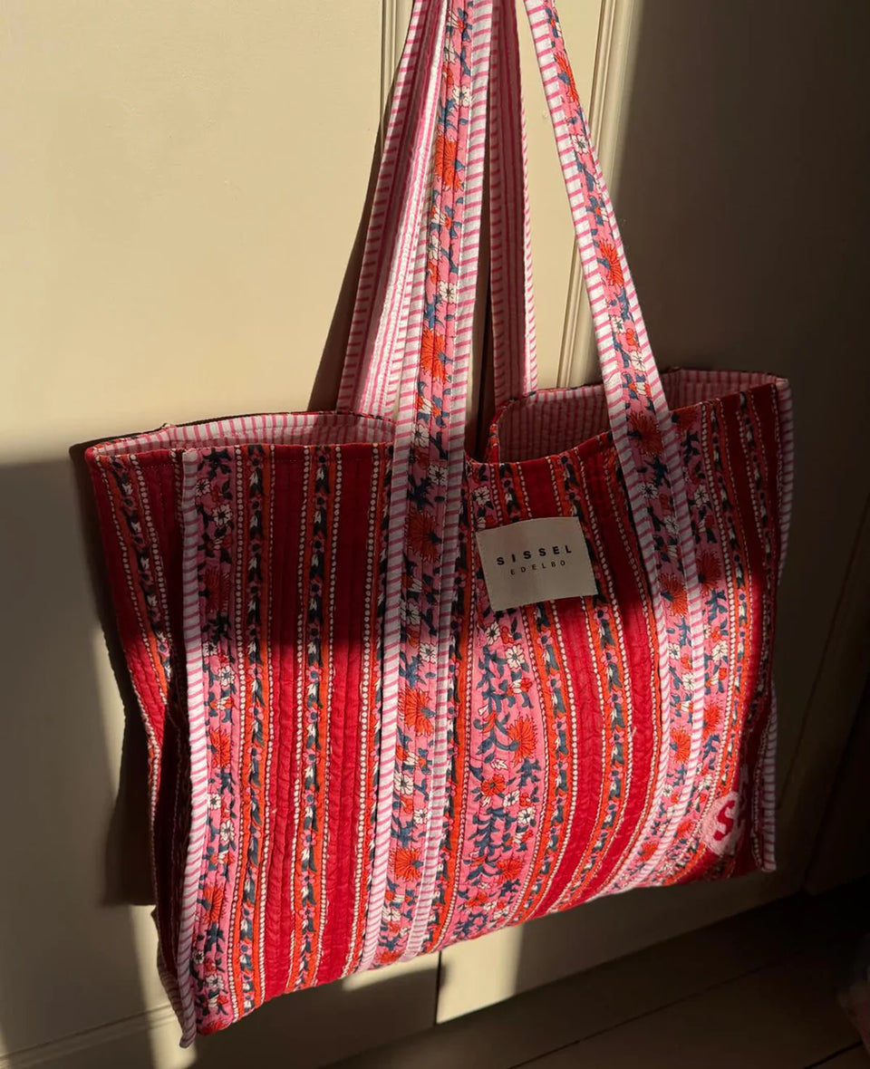 Duża torba typu shopper Pricilla Lavender Bloom SISSEL EDELBO z ręcznie wykonanym, kwiatowym printem i haftem. Wewnątrz posiada płócienną podszewkę i niewielką kieszonkę. Idealna na plażę, weekendowy wyjazd czy zakupy na targu.&nbsp;