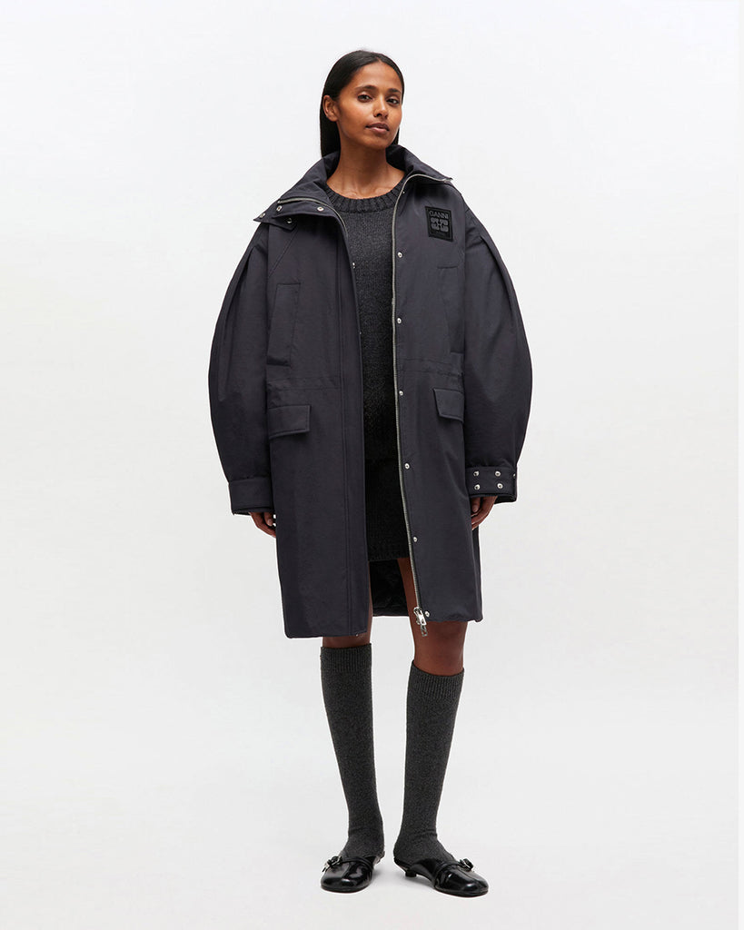 Luźny, prosty płaszcz typu parka 1012 Ganni Phantom o długości do kolan, z kapturem i mankietami. Posiada ściągacz w pasie i u dołu. Ma cztery kieszenie z przodu oraz kieszeń wewnętrzną. Nad lewą piersią znajduje się niewielka naszywka z logo marki.&nbsp;Zapinany za dwustronny zamek i srebrne, zatrzaskowe guziki.&nbsp;