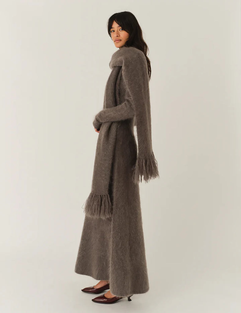 Bardzo długa, prosta sukienka Roma Grey Melange o długości do kostek. Jest delikatnie dopasowana do sylwetki, ale nie obcisła. Ma luźniejszy, swobodny charakter. Ma długie, wąskie rękawy oraz prosty dekolt. Wykonana z puszystej dzianiny z moheru. Zestaw ją ze szpilkami i delikatną biżuterią, aby uzyskać elegancki look lub z ciężkimi butami i noś ją na codzień.&nbsp;