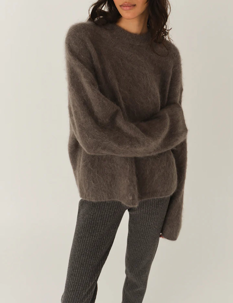 Bardzo miękki, oversizowy sweter Roma Grey Melange z okrągłym dekoltem i długimi, luźnymi rękawami. Wykonany z dzianiny z moherem. Idealny do spodni i spódnic z wysokim stanem.
