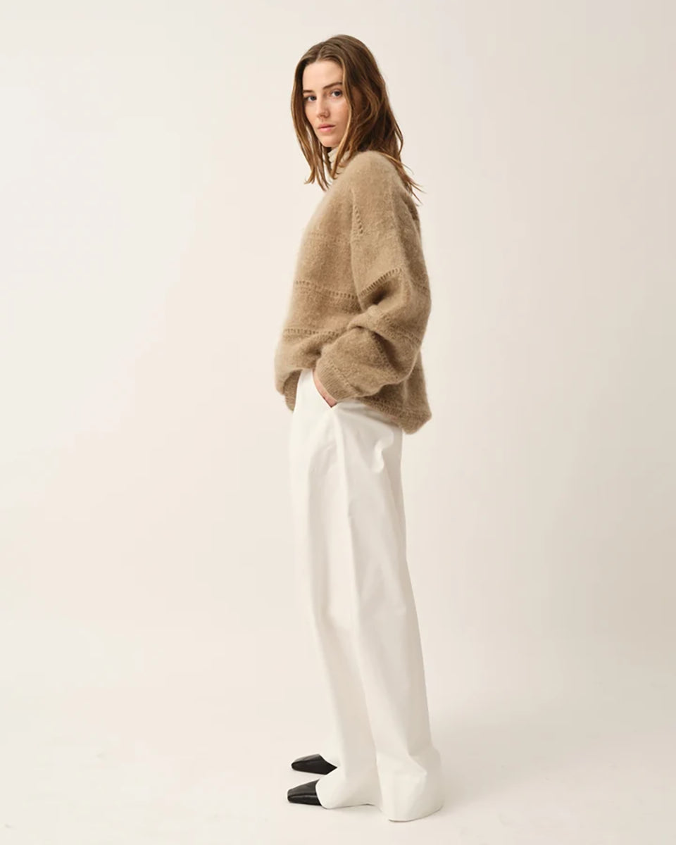 Luźny, oversizowy sweter Roma The Garment w klasycznym odcieniu jasnego brązu. Posiada prosty, okrągły dekolt i lekko opadające ramiona. Sweter ma długie rękawy. Jego powierzchnię wyróżnia urozmaicona faktura- gładką dzianinę przeplatają poziome pasy o dekoracyjnym, ażurowym splocie, które dodają całości lekkości i unikalnego charakteru. Jest wykończony ściągaczami. Wykonany z puchatej dzianiny z moherem.

-Luźny fason

-Okrągły dekolt

-Dzianina z moherem

-Zamów sweter w swoim normalnym rozmiarze