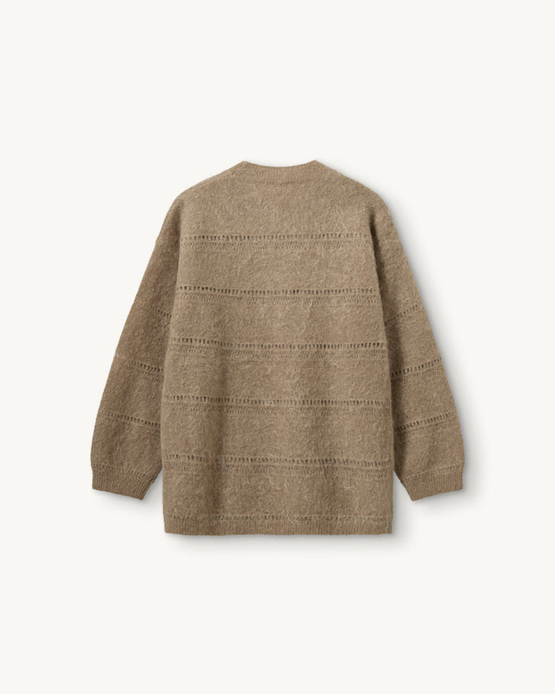 Luźny, oversizowy sweter Roma The Garment w klasycznym odcieniu jasnego brązu. Posiada prosty, okrągły dekolt i lekko opadające ramiona. Sweter ma długie rękawy. Jego powierzchnię wyróżnia urozmaicona faktura- gładką dzianinę przeplatają poziome pasy o dekoracyjnym, ażurowym splocie, które dodają całości lekkości i unikalnego charakteru. Jest wykończony ściągaczami. Wykonany z puchatej dzianiny z moherem.

-Luźny fason

-Okrągły dekolt

-Dzianina z moherem

-Zamów sweter w swoim normalnym rozmiarze
