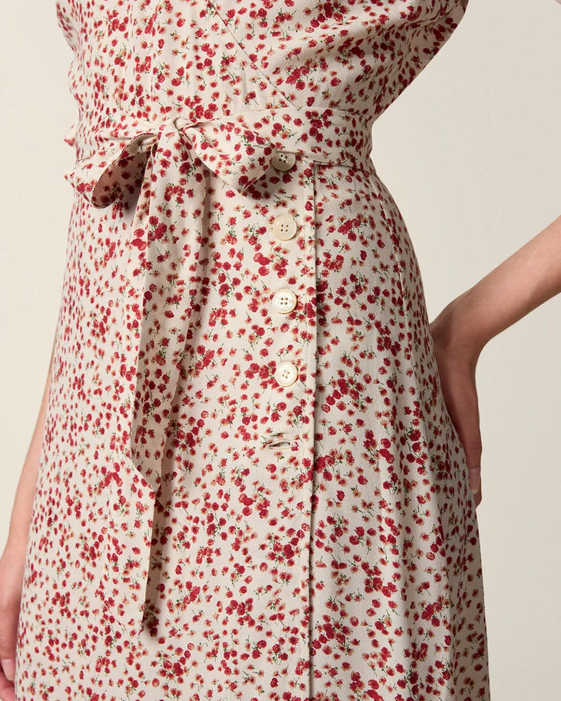 Zwiewna, kopertowa sukienka w kwiatowy print Rosalina Rouje z krótkimi, bufiastymi rękawami i trójkątnym dekoltem. Dopasowana i wiązana w talii za pomocą paska. Sukienka ma długość za kolana. 