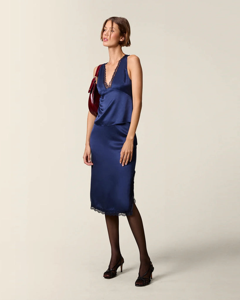 Elegancki, satynowy top na szerokich ramiączkach Opal Rouje z głębokim, trójkątnym dekoltem obszytym zmysłową koronką. Odcięta pod biustem. Z tyłu, przy szyi zapinana na guzik. Na plecach posiada niewielkie rozcięcie i zapięcie na zamek błyskawiczny. Wykonana ze śliskiej tkaniny z jedwabiem.